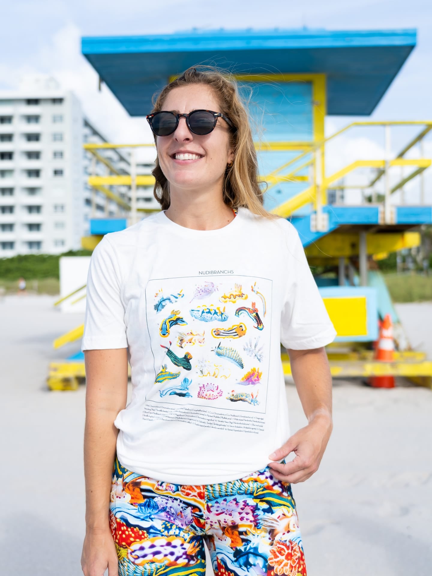 A white organic cotton tee with many colorful nudibranchs printed on the front along with their IDs.